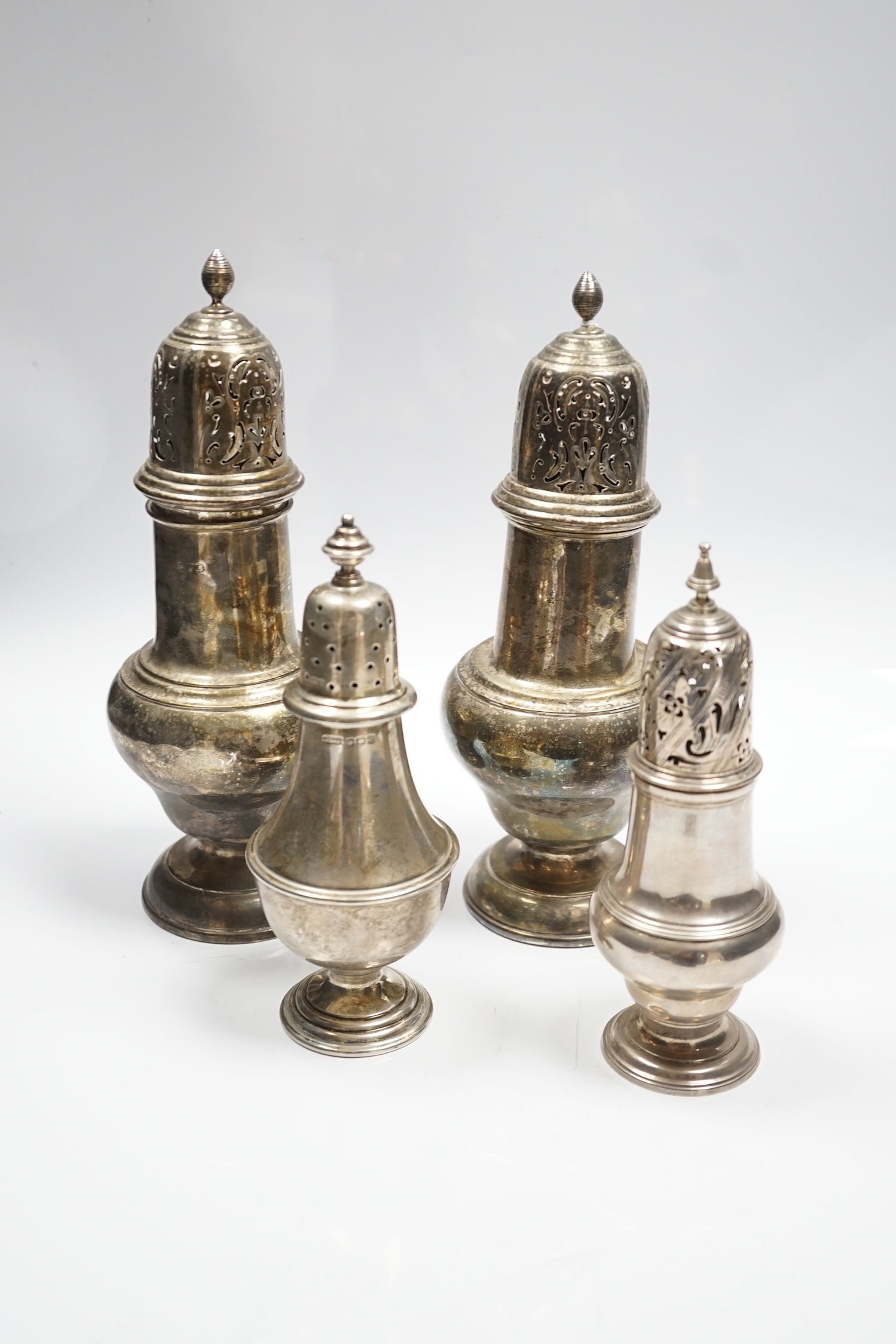 A pair of early to mid 20th century large silver sugar casters, marks rubbed, 23.8cm, weighted and two smaller silver sugar casters including George III, London, 1764.